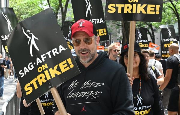 A photo including Actor and Writers Guild of America member Jason Sudeikis as he walks the Picket Line outside of NBC.