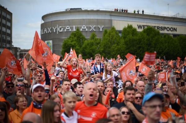 Supporters hold up placards and flags as they  welcome the bus of Luton Town football club players and staff during a parade through the streets of Luton with the Champio<em></em>nship playoff trophy, in Luton, north of Lo<em></em>ndon on May 29, 2023, as they celebrate their promotion to the English Premier League. — AFP pic